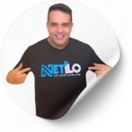 Imagem de um homem sorridente vestindo uma camiseta preta com a logomarca da Netilo, uma agência de marketing digital em Brasília. Ele está apontando para o logotipo da empresa, que é colorido em azul e branco.